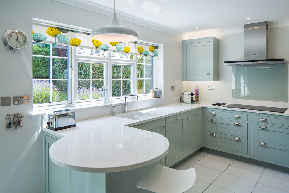 This is an example of a midcentury l-shaped kitchen in Hertfordshire with an undermount sink, shaker cabinets, blue cabinets, a peninsula and white floor.