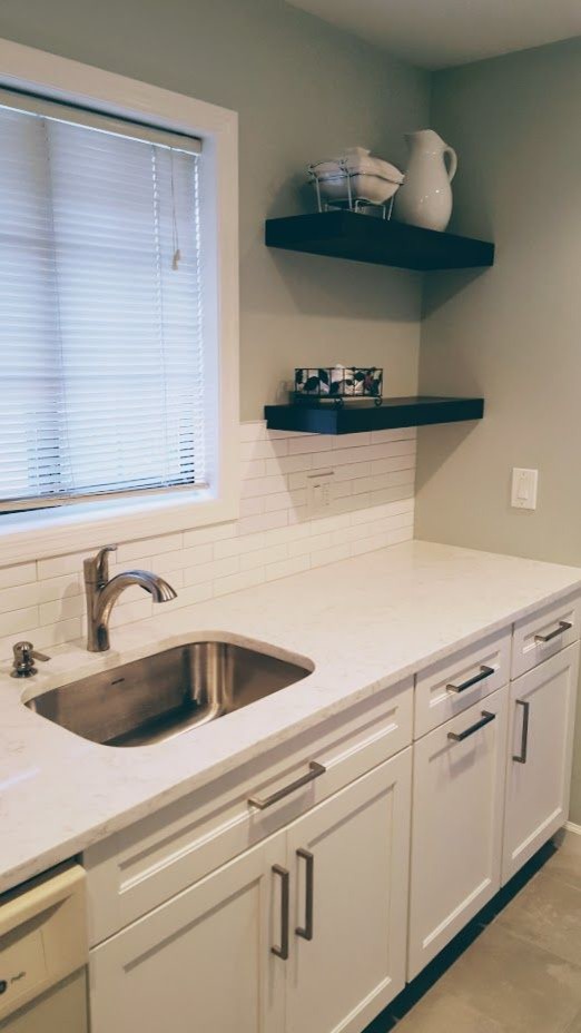 Example of a small transitional brown floor kitchen design with an undermount sink, shaker cabinets, white cabinets, quartz countertops, white backsplash, subway tile backsplash, stainless steel appliances, no island and white countertops