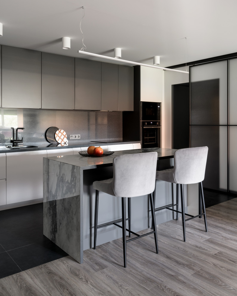 Design ideas for a contemporary single-wall eat-in kitchen in Novosibirsk with an undermount sink, flat-panel cabinets, white cabinets, solid surface benchtops, grey splashback, engineered quartz splashback, black appliances, porcelain floors, with island, black floor and grey benchtop.