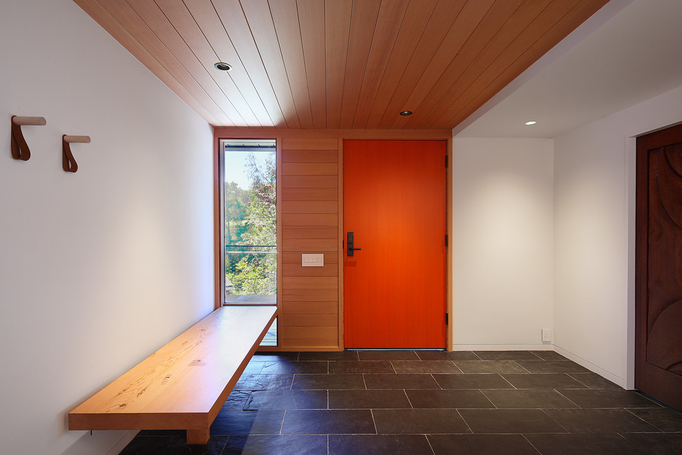 This is an example of a large contemporary foyer in San Francisco with white walls, a single front door, an orange front door, grey floor and slate floors.