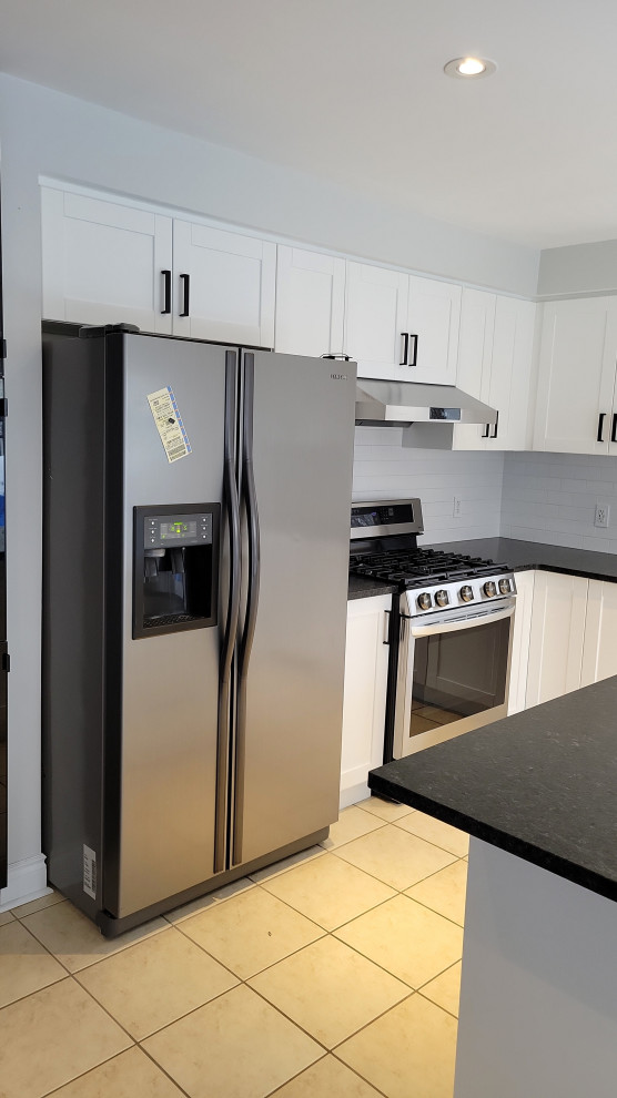 Transitional kitchen photo with an undermount sink, recessed-panel cabinets, white cabinets, granite countertops, gray backsplash, porcelain backsplash and black countertops