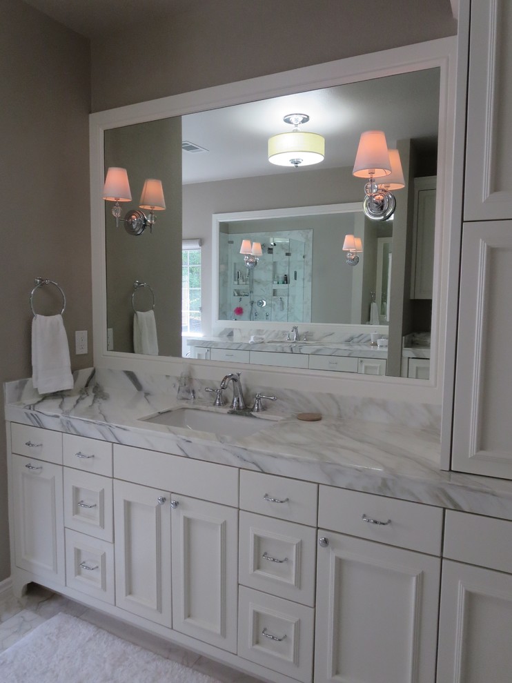 Photo of a large transitional master bathroom in Austin with recessed-panel cabinets, white cabinets, gray tile, grey walls, an undermount sink, marble benchtops, an undermount tub, a corner shower, a two-piece toilet, porcelain tile and porcelain floors.