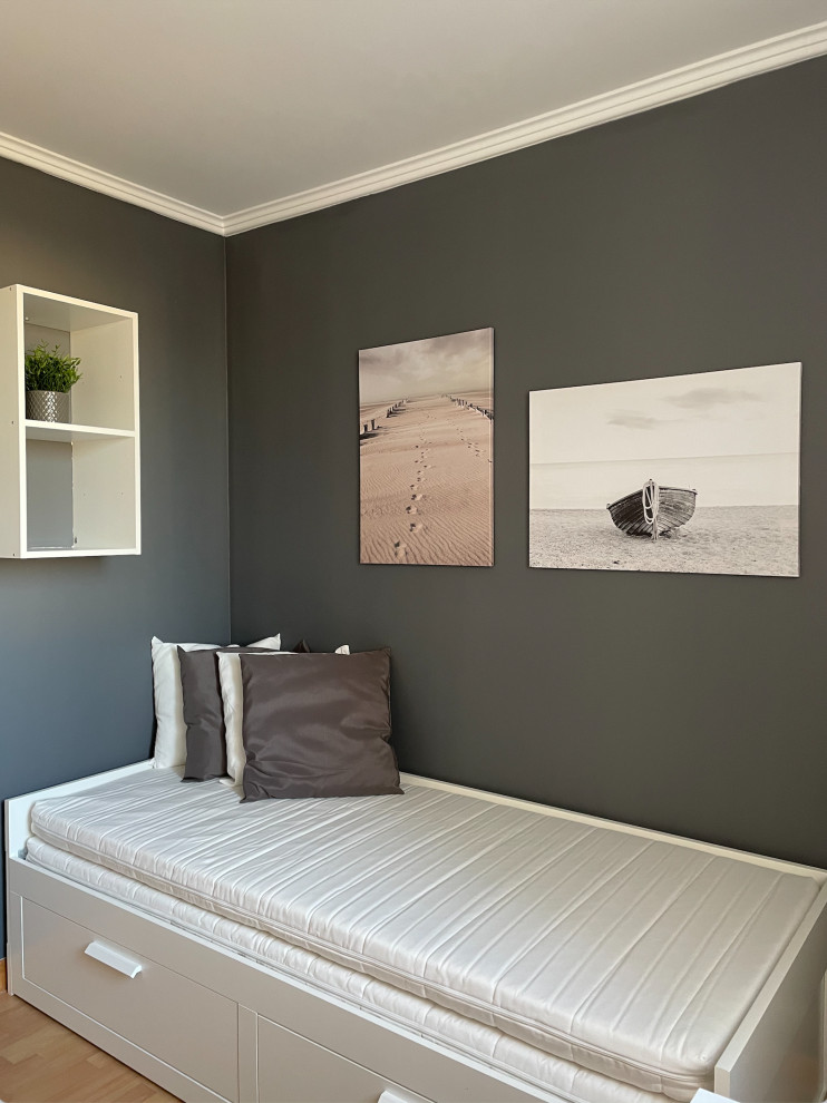 This is an example of a medium sized modern guest and grey and white bedroom in Paris with grey walls, laminate floors and brown floors.