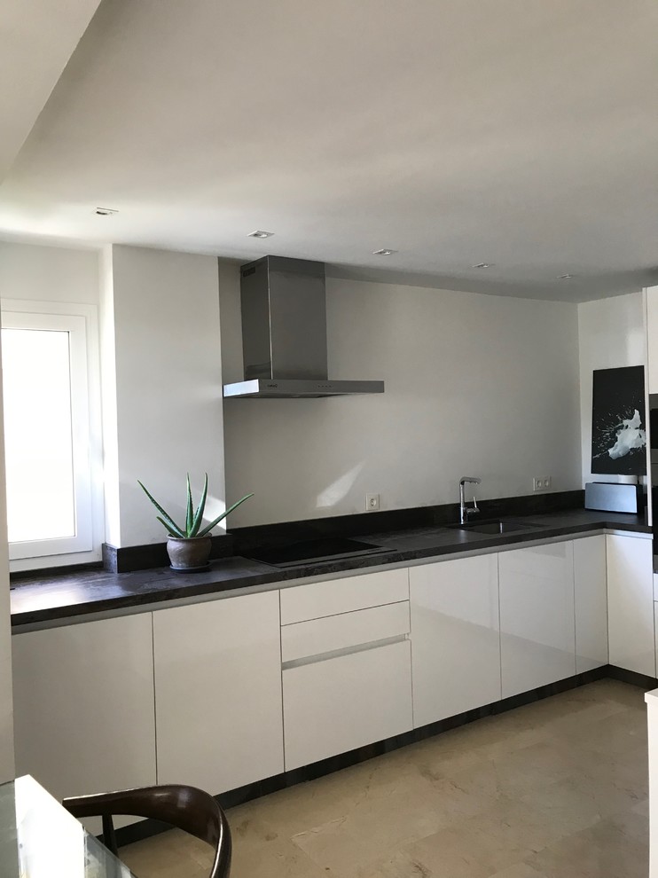 Photo of a mid-sized modern l-shaped eat-in kitchen in Malaga with flat-panel cabinets, white cabinets, quartz benchtops, an undermount sink, brown splashback, stone slab splashback, terrazzo floors, beige floor and white appliances.