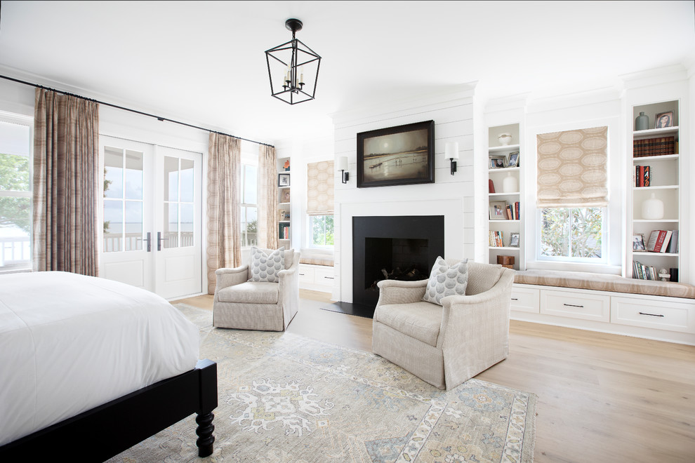 Photo of a transitional guest bedroom in Charleston with white walls, light hardwood floors, a standard fireplace and beige floor.