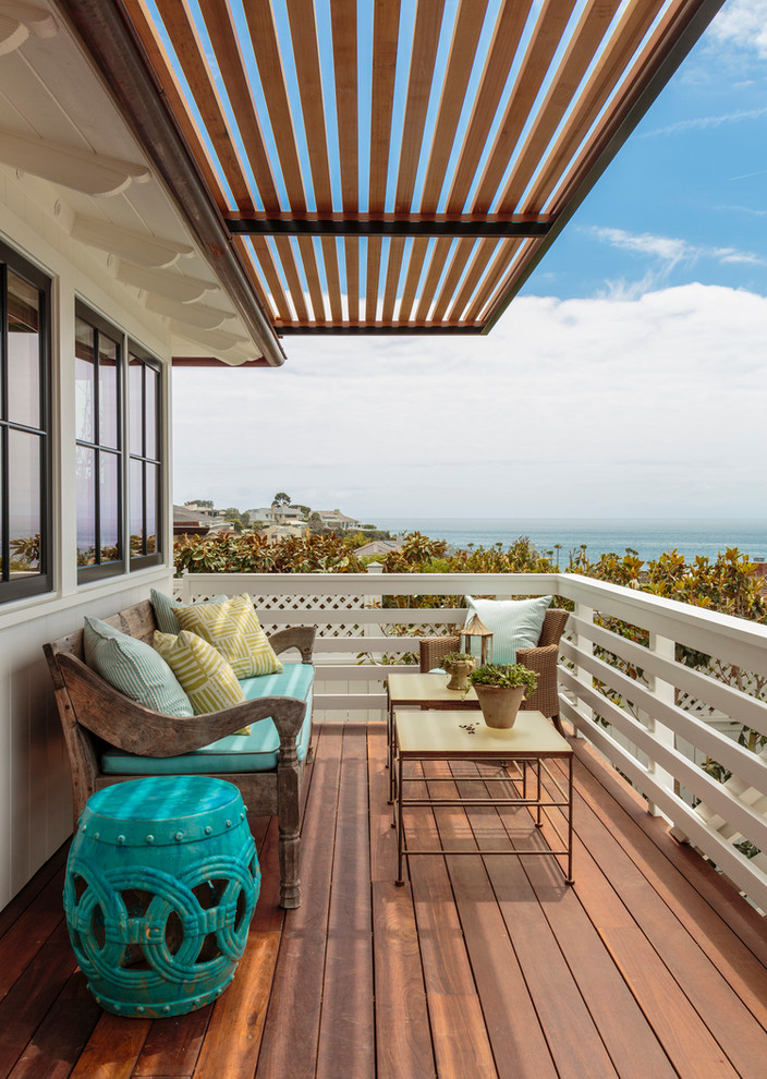 Photo of a beach style balcony in Orange County with a roof extension and wood railing.