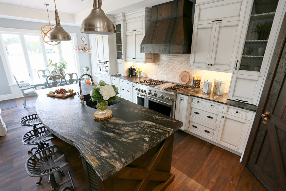 Large mountain style l-shaped dark wood floor and brown floor open concept kitchen photo in Toronto with an undermount sink, recessed-panel cabinets, white cabinets, beige backsplash, glass tile backsplash, stainless steel appliances, an island, onyx countertops and black countertops