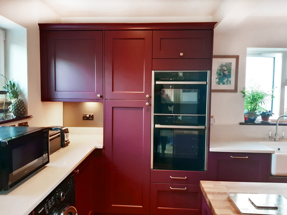 Geschlossene, Kleine Klassische Küche in U-Form mit Schrankfronten im Shaker-Stil, roten Schränken, Quarzit-Arbeitsplatte, Kücheninsel und weißer Arbeitsplatte in Cornwall