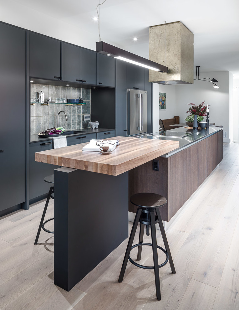 Design ideas for a mid-sized modern galley eat-in kitchen in Ottawa with an undermount sink, flat-panel cabinets, grey cabinets, stainless steel benchtops, grey splashback, stainless steel appliances, light hardwood floors and with island.