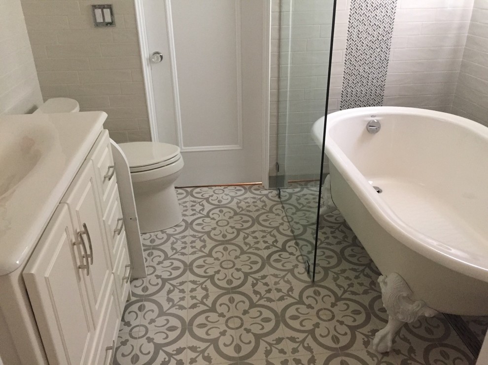 Photo of a mid-sized mediterranean 3/4 bathroom in Los Angeles with furniture-like cabinets, white cabinets, a claw-foot tub, a shower/bathtub combo, a one-piece toilet, gray tile, subway tile, grey walls, cement tiles, an integrated sink, tile benchtops, grey floor and an open shower.