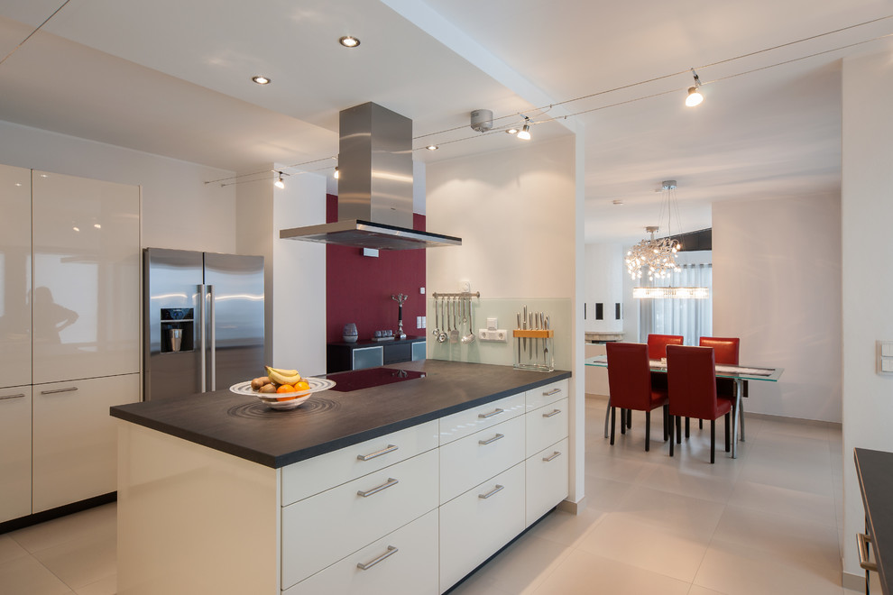 Large contemporary u-shaped open plan kitchen in Dresden with flat-panel cabinets, white cabinets, glass sheet splashback, stainless steel appliances, ceramic floors and a peninsula.