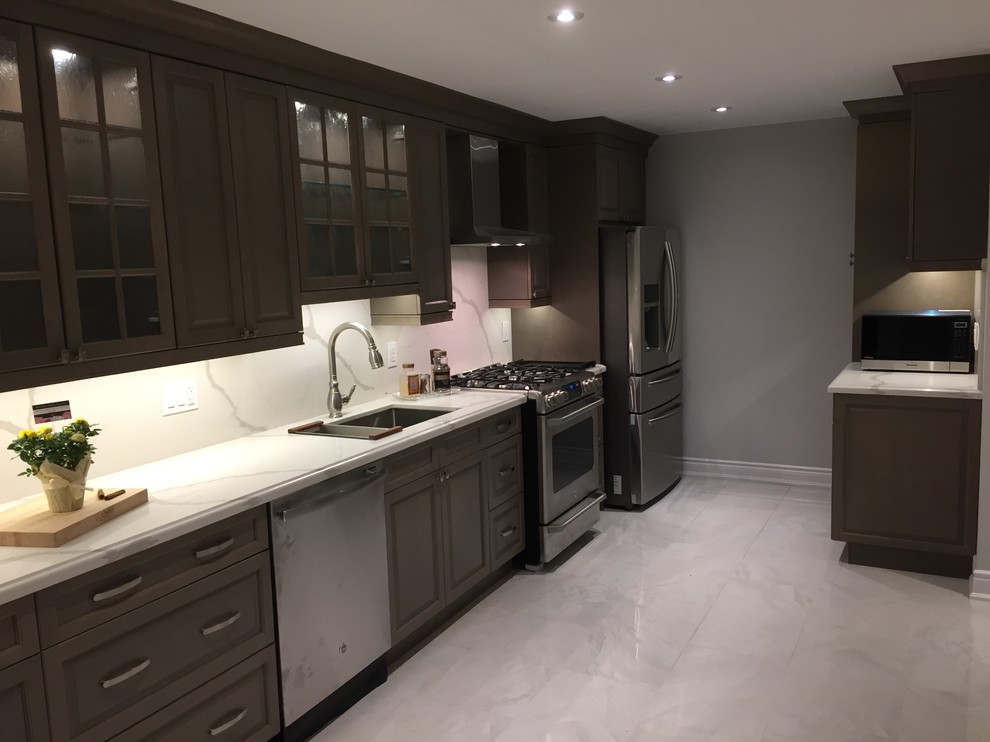 Photo of a mid-sized traditional galley eat-in kitchen in Toronto with an undermount sink, shaker cabinets, light wood cabinets, marble benchtops, white splashback, stainless steel appliances, porcelain floors, white floor and white benchtop.