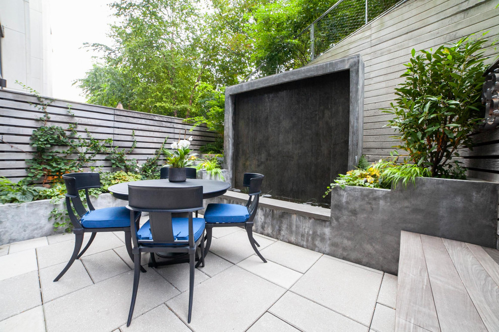 Mid-sized modern backyard and ground level deck in New York with a water feature, no cover and wood railing.