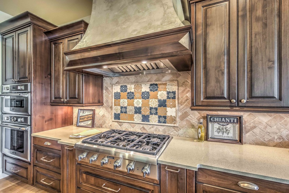Example of a large transitional l-shaped dark wood floor eat-in kitchen design in Boise with an undermount sink, raised-panel cabinets, white cabinets, solid surface countertops, beige backsplash, subway tile backsplash, stainless steel appliances and an island