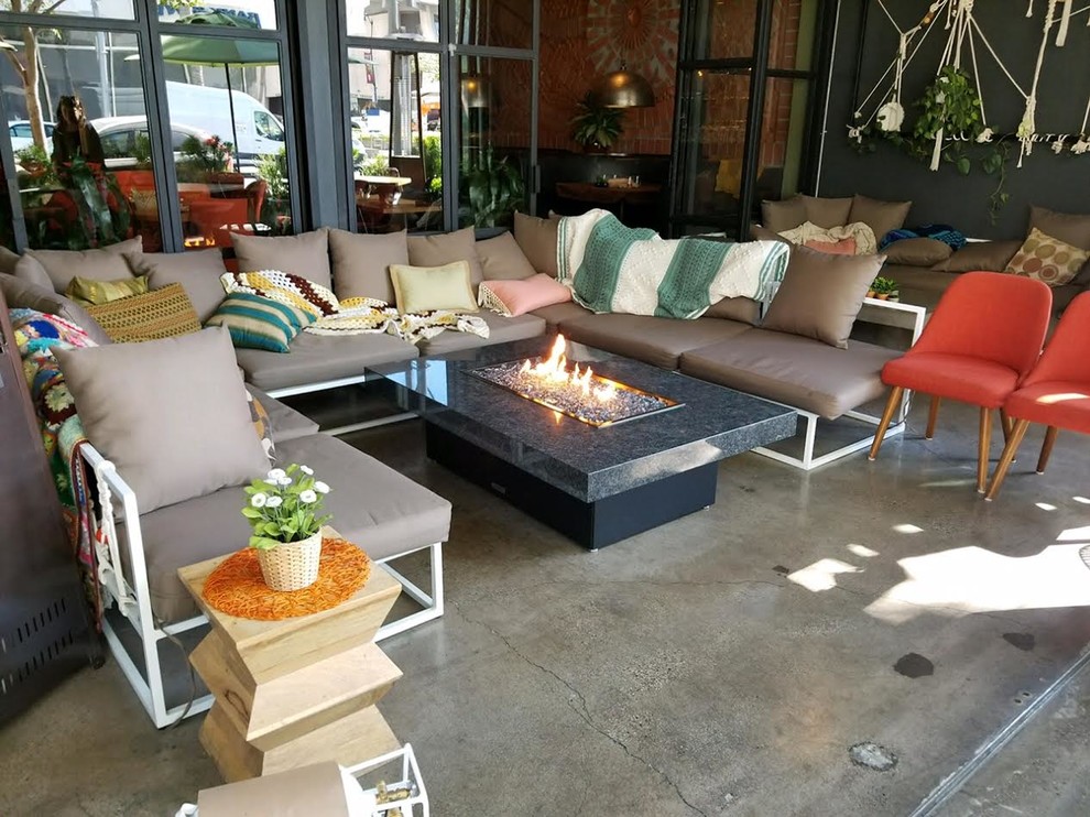 Photo of a mid-sized eclectic courtyard patio in Los Angeles with a fire feature, concrete slab and a roof extension.