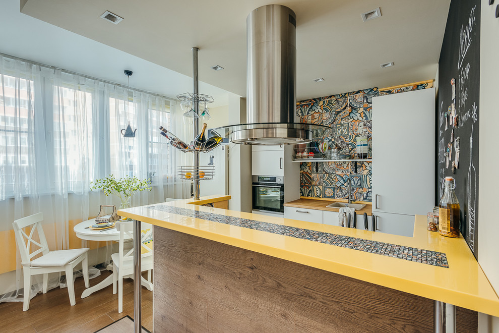 Photo of a small scandinavian galley eat-in kitchen in Moscow with flat-panel cabinets, white cabinets, brown floor, yellow benchtop, a single-bowl sink, solid surface benchtops, yellow splashback, ceramic splashback, stainless steel appliances, porcelain floors and with island.