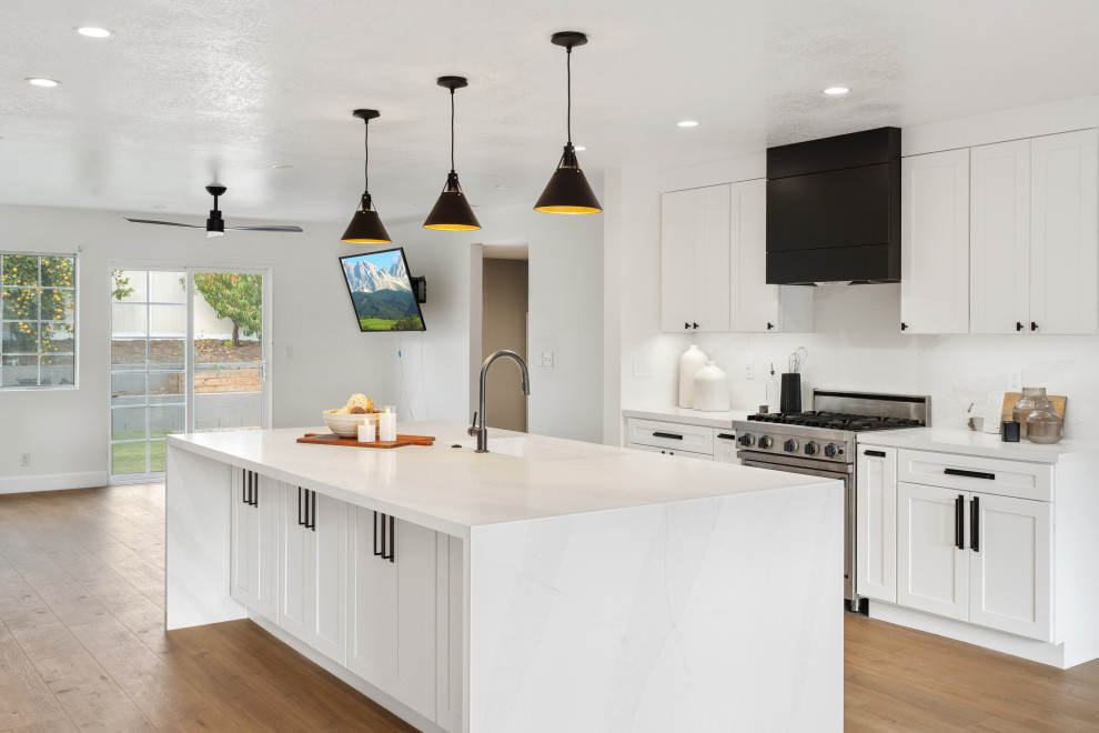 Mid-sized transitional vinyl floor and brown floor open concept kitchen photo in Orange County with an undermount sink, shaker cabinets, white cabinets, quartz countertops, white backsplash, quartz backsplash, stainless steel appliances, an island and white countertops