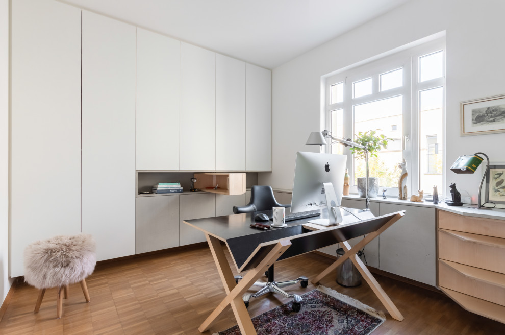Kleines Modernes Arbeitszimmer mit Arbeitsplatz, weißer Wandfarbe, hellem Holzboden, freistehendem Schreibtisch und braunem Boden in Düsseldorf
