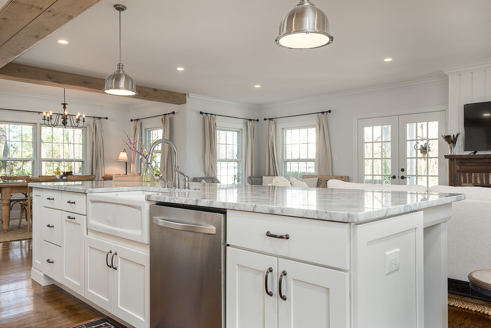 Example of a mid-sized transitional galley medium tone wood floor and brown floor open concept kitchen design with a farmhouse sink, shaker cabinets, white cabinets, granite countertops, white backsplash, subway tile backsplash, stainless steel appliances and an island