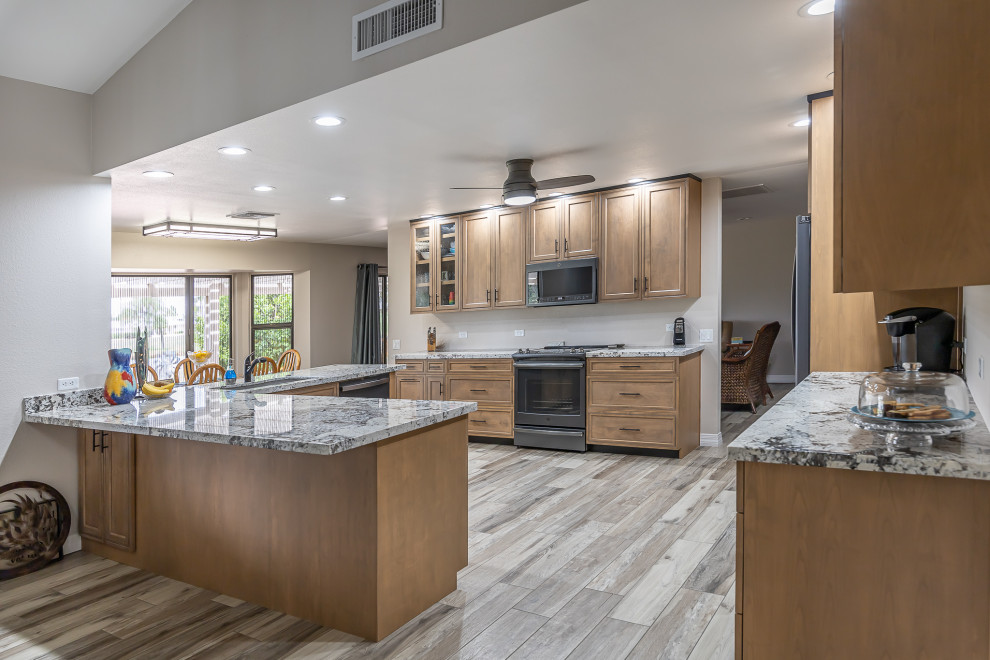 Inspiration for a mid-sized modern open plan kitchen in Phoenix with an undermount sink, shaker cabinets, medium wood cabinets, granite benchtops, black appliances, porcelain floors, a peninsula, beige floor and yellow benchtop.