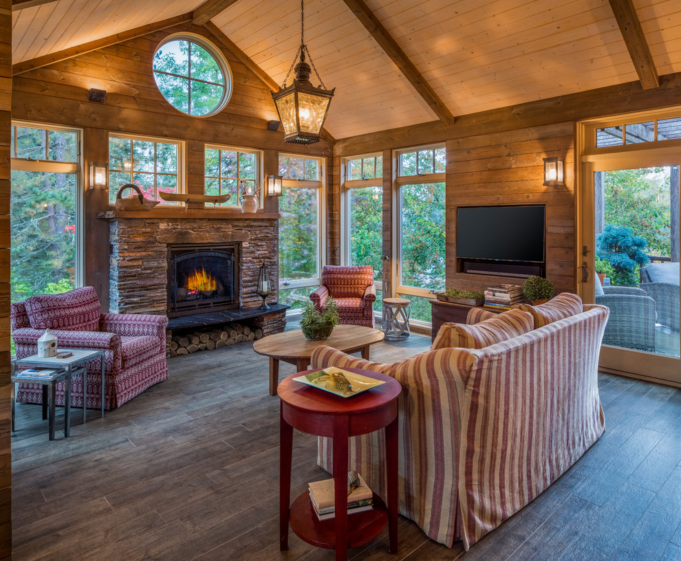 This is an example of a country sunroom in Portland with dark hardwood floors, a standard fireplace, a stone fireplace surround, a standard ceiling and brown floor.