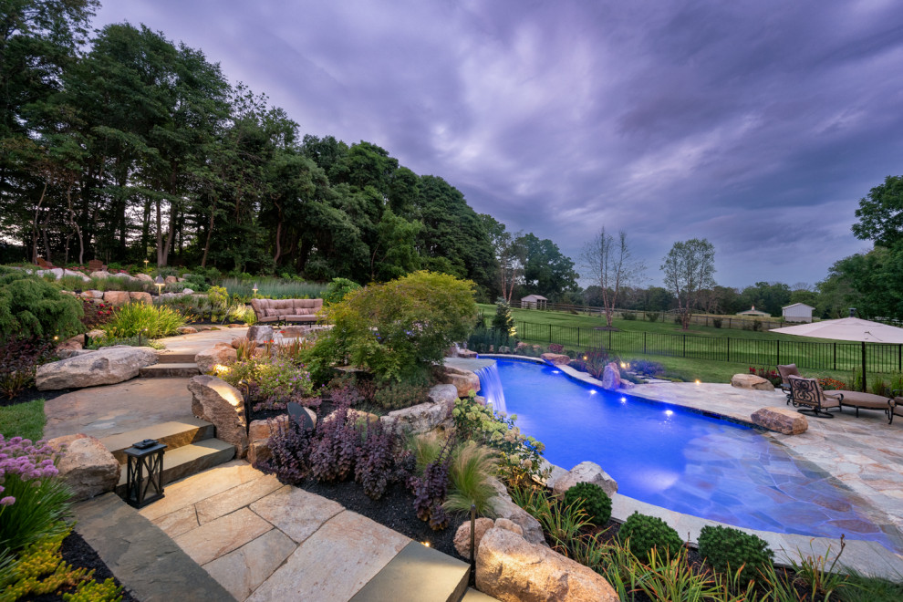 Imagen de piscina natural rural grande a medida en patio trasero con paisajismo de piscina y adoquines de piedra natural