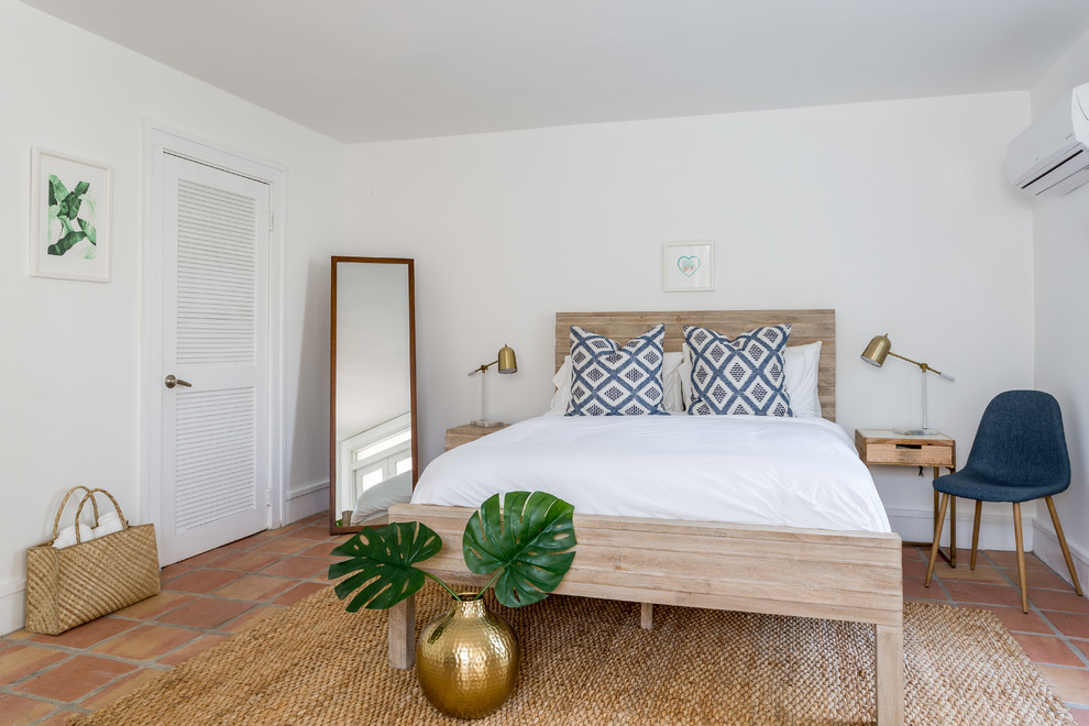 This is an example of a beach style bedroom in Other with terra-cotta floors.