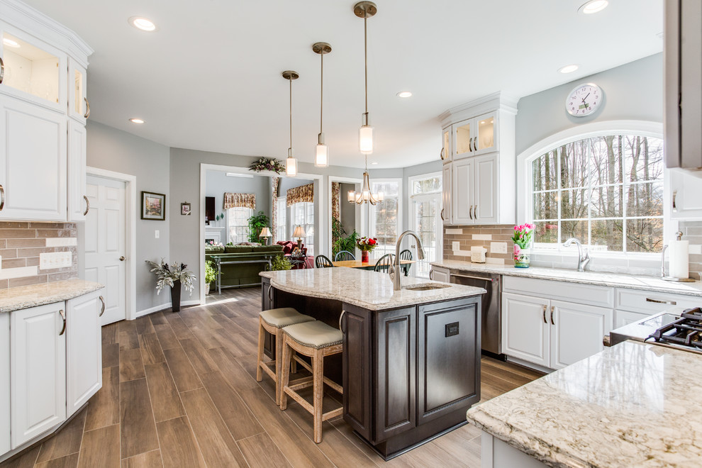 Eat-in kitchen - large transitional u-shaped porcelain tile and brown floor eat-in kitchen idea in DC Metro with a single-bowl sink, raised-panel cabinets, white cabinets, quartz countertops, gray backsplash, ceramic backsplash, stainless steel appliances and an island