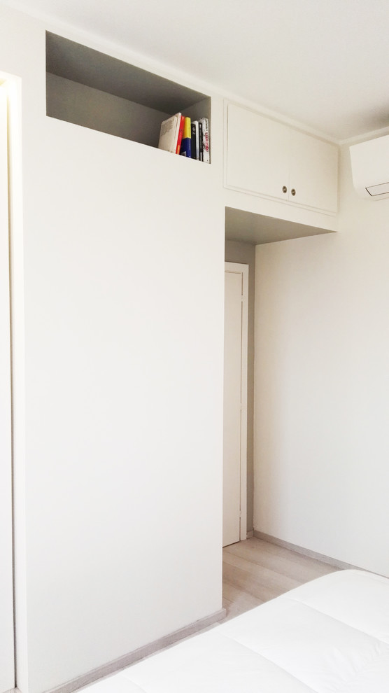 Inspiration for a mid-sized modern gender-neutral built-in wardrobe in Bologna with light wood cabinets, light hardwood floors, beige floor and flat-panel cabinets.