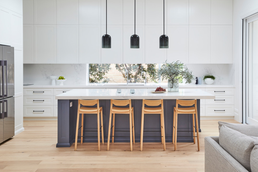 Traditional l-shaped kitchen in Sydney with shaker cabinets, blue cabinets, quartz benchtops, white splashback, engineered quartz splashback, light hardwood floors and with island.