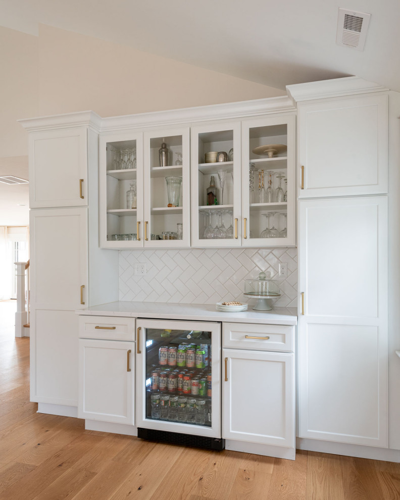 Eat-in kitchen - huge transitional l-shaped light wood floor, brown floor and vaulted ceiling eat-in kitchen idea in Boston with an undermount sink, shaker cabinets, white cabinets, quartz countertops, white backsplash, ceramic backsplash, paneled appliances, an island and white countertops