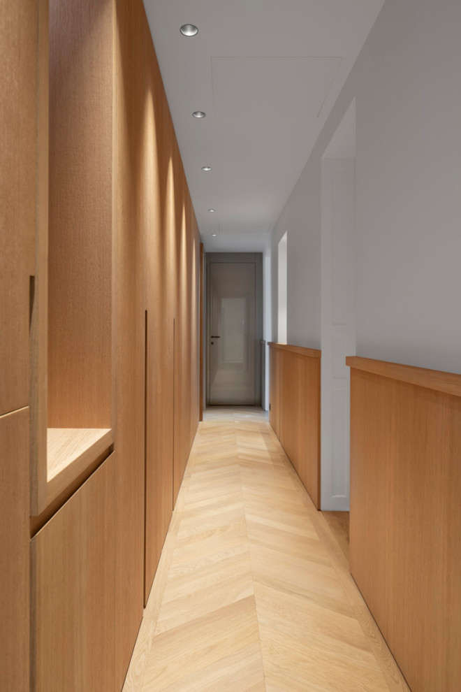 На фото: большой коридор в стиле неоклассика (современная классика) с белыми стенами, светлым паркетным полом, бежевым полом и деревянными стенами с