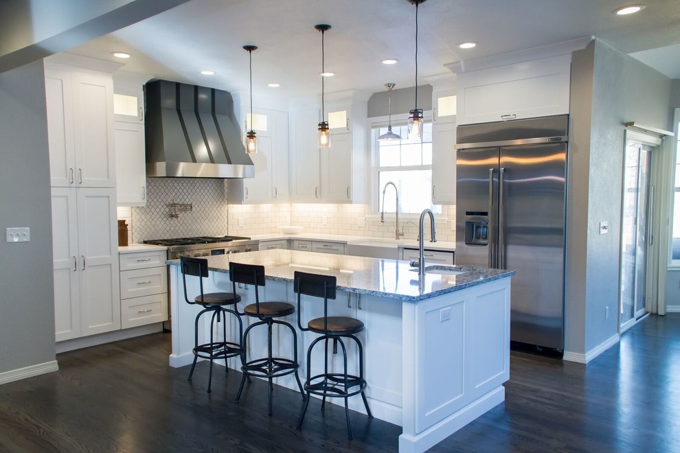 Eat-in kitchen - mid-sized transitional l-shaped dark wood floor and brown floor eat-in kitchen idea in Denver with a farmhouse sink, shaker cabinets, white cabinets, quartz countertops, white backsplash, porcelain backsplash, stainless steel appliances and an island