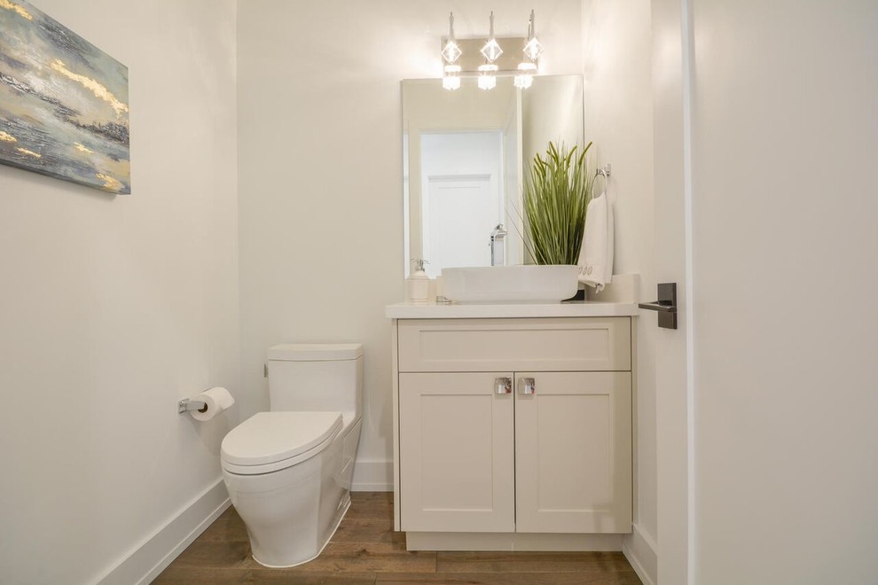 Contemporary 3/4 bathroom in Miami with shaker cabinets, a one-piece toilet, white tile, white walls, medium hardwood floors, a vessel sink, solid surface benchtops and brown floor.
