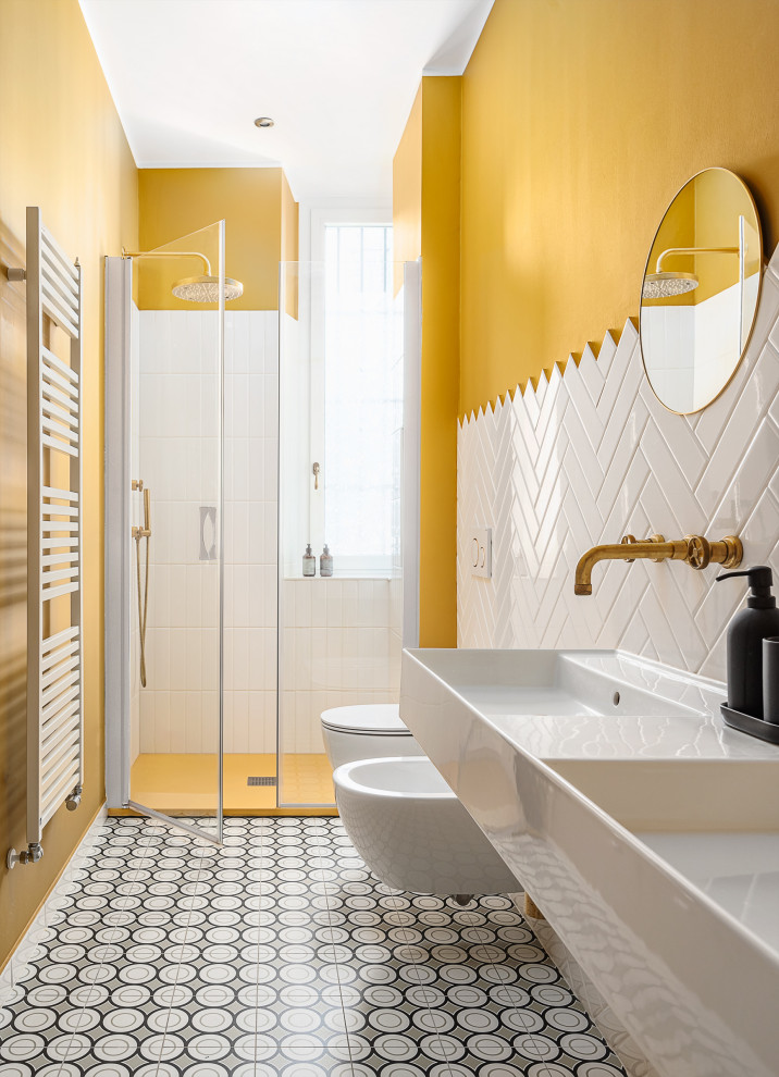 Идея дизайна: узкая и длинная ванная комната среднего размера в классическом стиле с душем без бортиков, раздельным унитазом, белой плиткой, керамогранитной плиткой, желтыми стенами, полом из цементной плитки, душевой кабиной, подвесной раковиной, серым полом, душем с распашными дверями, тумбой под две раковины и многоуровневым потолком
