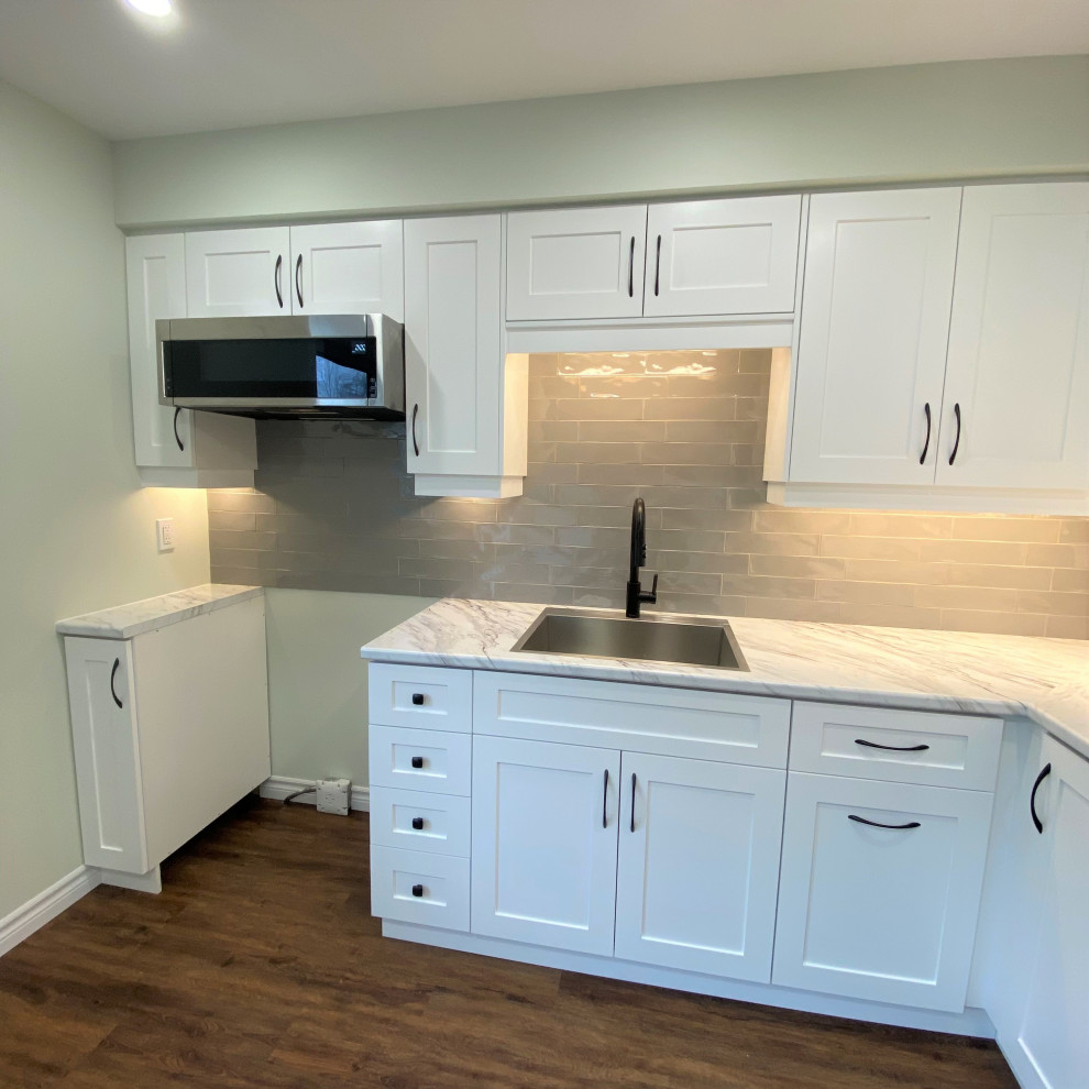 Eat-in kitchen - mid-sized transitional galley vinyl floor eat-in kitchen idea in Toronto with a drop-in sink, shaker cabinets, white cabinets, laminate countertops, gray backsplash and stainless steel appliances
