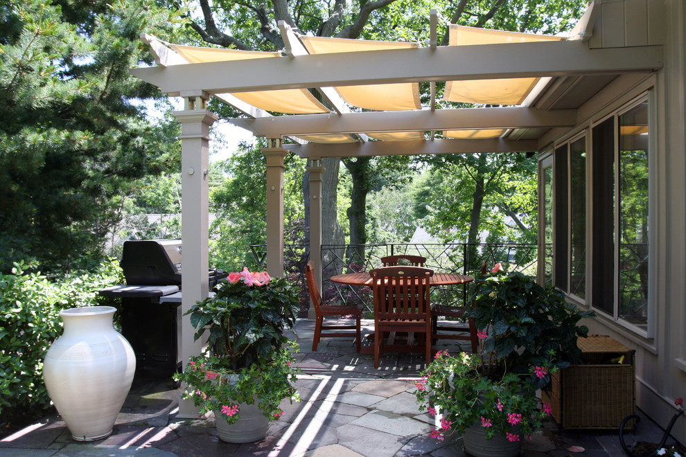 Mid-sized eclectic backyard patio in Boston with an outdoor kitchen, natural stone pavers and an awning.