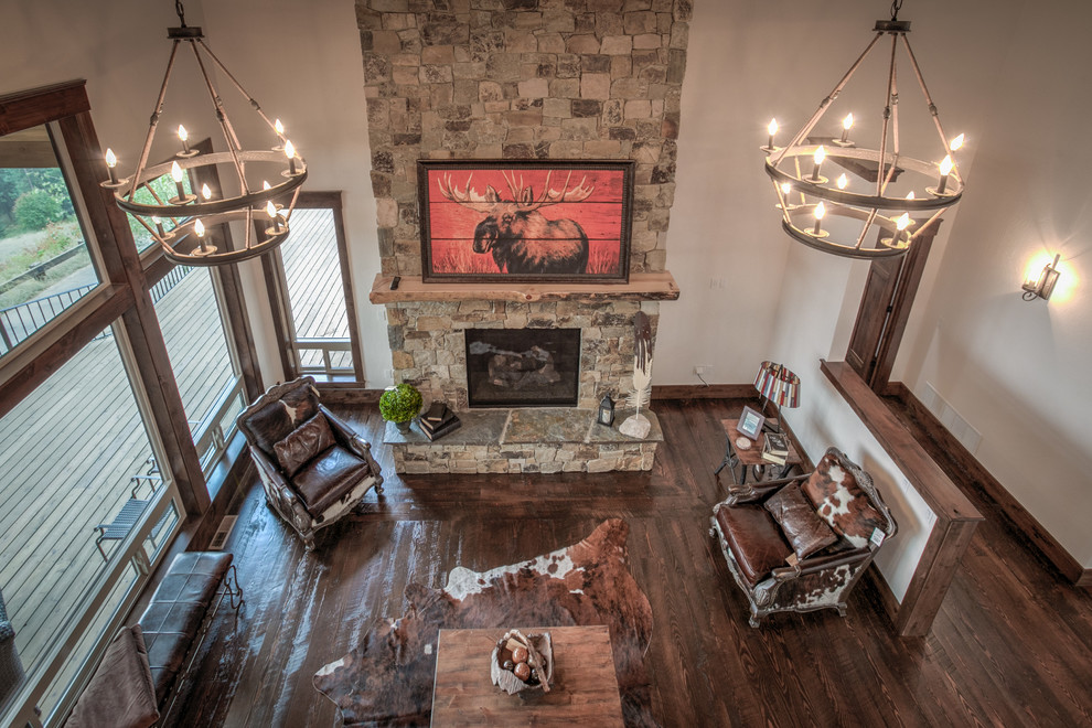 This is an example of a mid-sized country loft-style living room in Seattle with white walls, dark hardwood floors, a standard fireplace, a stone fireplace surround and no tv.