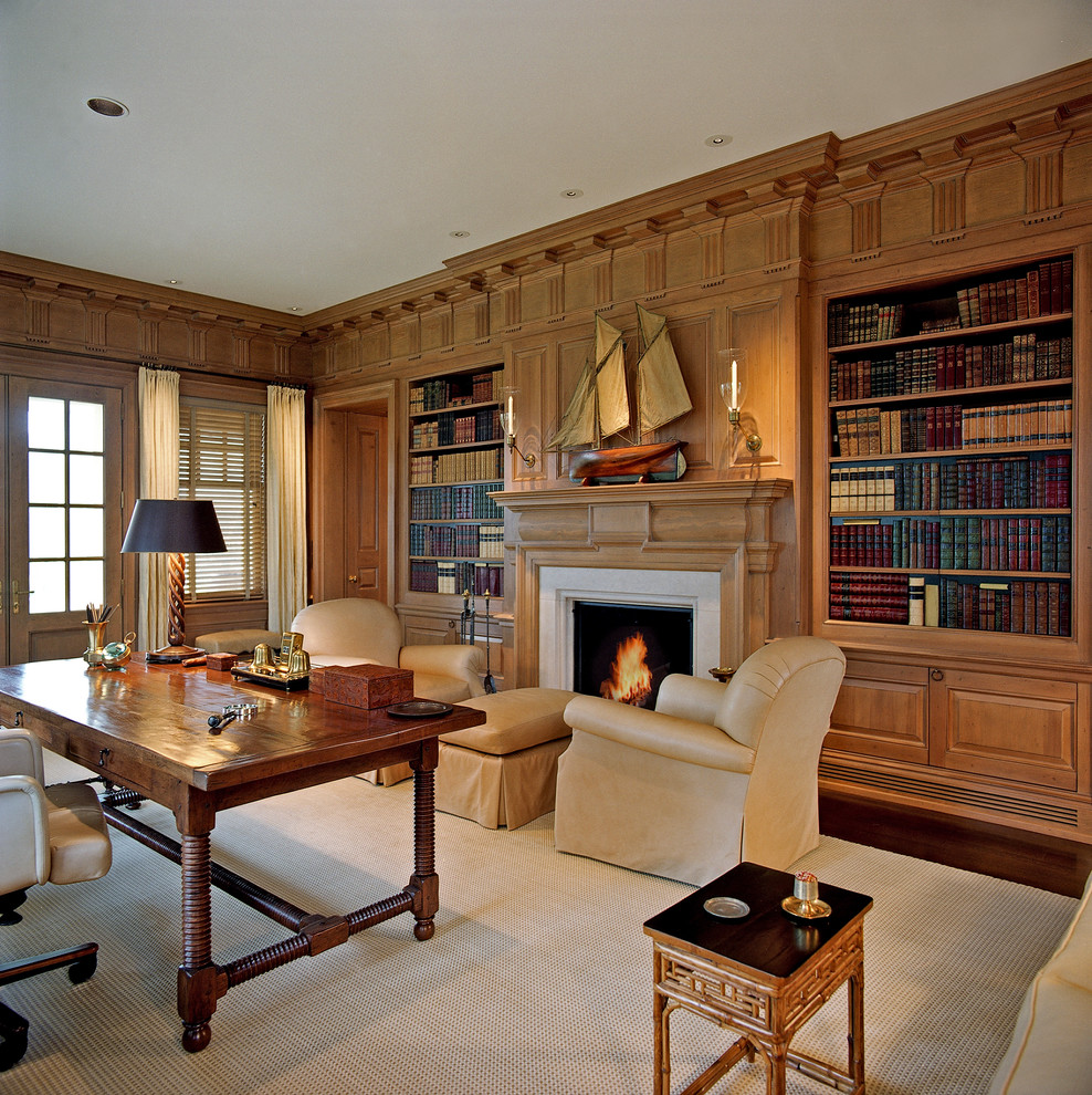 This is an example of a large traditional study room in New York with brown walls, carpet, a standard fireplace, a stone fireplace surround and a freestanding desk.