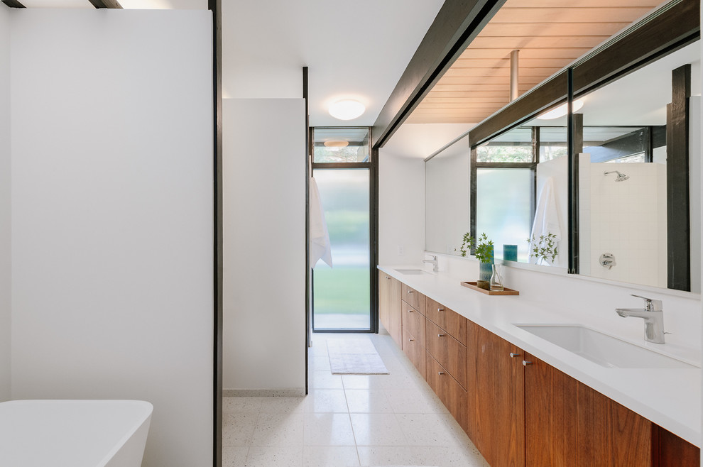 Photo of a large midcentury master bathroom in Los Angeles with flat-panel cabinets, medium wood cabinets, a freestanding tub, an open shower, an undermount sink, solid surface benchtops, white floor, an open shower and white benchtops.