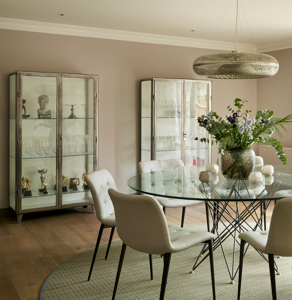 This is an example of an industrial dining room in London with grey walls and medium hardwood floors.