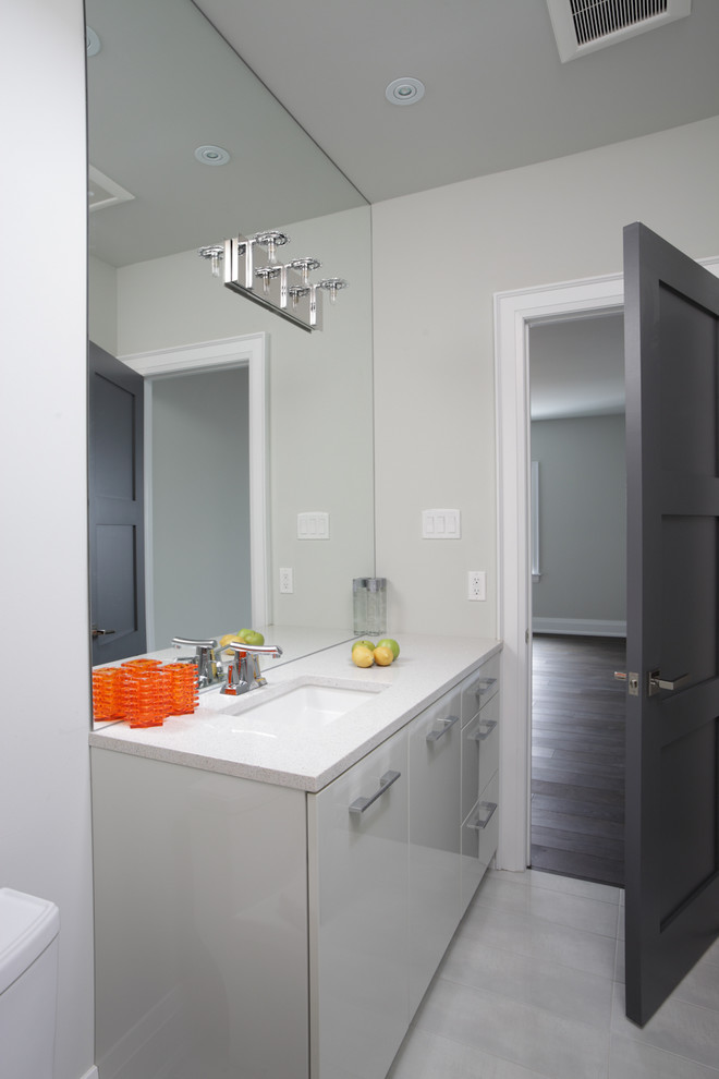 Inspiration for a small modern bathroom in Toronto with flat-panel cabinets, white cabinets, a freestanding tub, a two-piece toilet, gray tile, multi-coloured tile, white tile, grey walls, an undermount sink and granite benchtops.