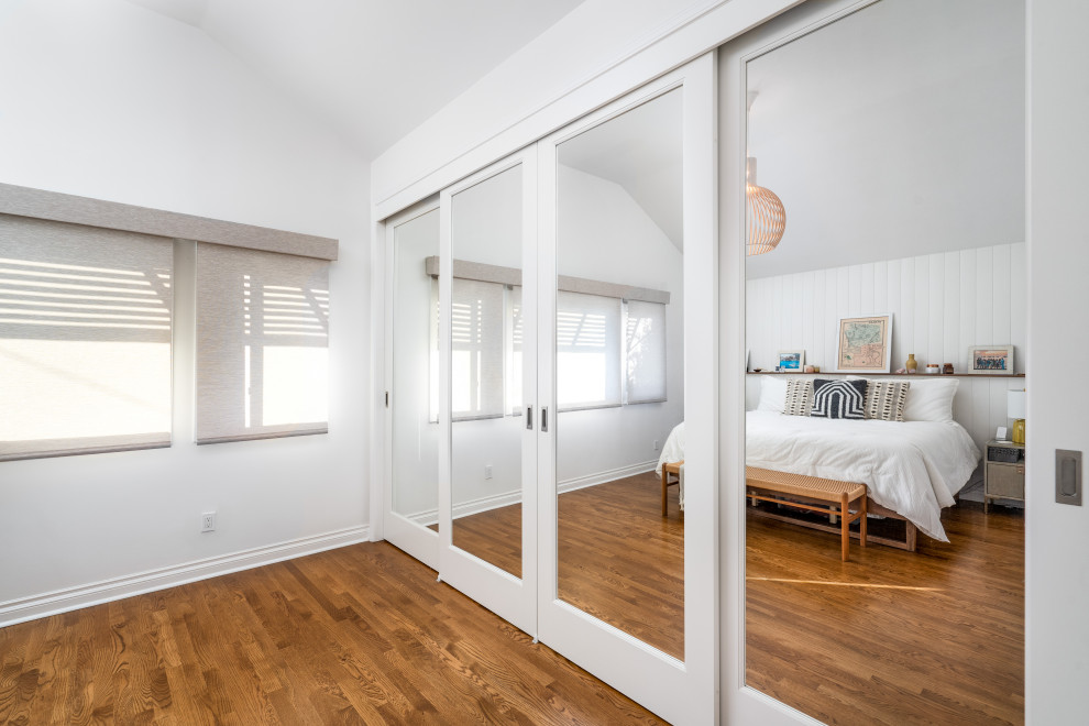 Aménagement d'une chambre d'amis contemporaine avec un mur blanc, parquet foncé, un sol multicolore et du lambris de bois.
