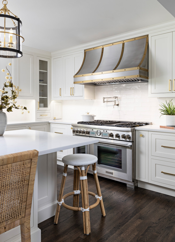 Inspiration for a mid-sized transitional u-shaped separate kitchen in Detroit with beaded inset cabinets, white cabinets, quartz benchtops, white splashback, subway tile splashback, stainless steel appliances, dark hardwood floors, with island, brown floor and white benchtop.