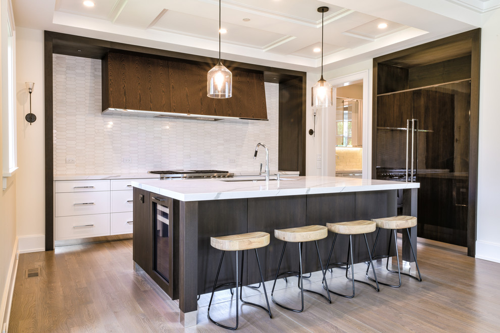 Inspiration for a large transitional galley medium tone wood floor and gray floor open concept kitchen remodel in Chicago with an undermount sink, flat-panel cabinets, quartz countertops, white backsplash, marble backsplash, paneled appliances, an island, white countertops and dark wood cabinets