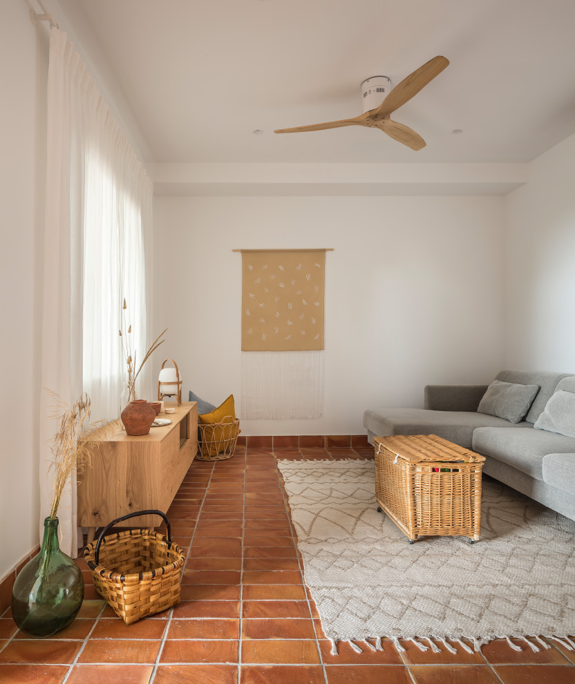 Idée de décoration pour une petite salle à manger ouverte sur la cuisine méditerranéenne avec un mur blanc, tomettes au sol et un sol marron.