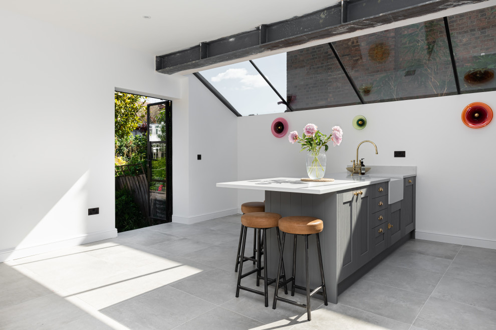 Inspiration for an industrial eat-in kitchen in London with grey cabinets, a peninsula, grey floor and white benchtop.