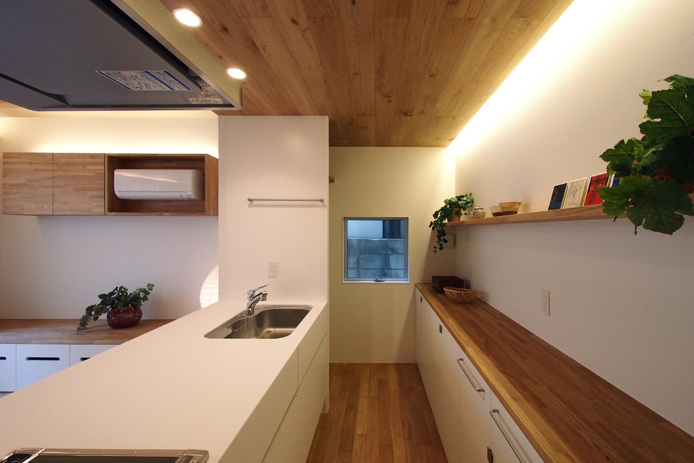 Photo of a mid-sized asian galley open plan kitchen in Tokyo Suburbs with an undermount sink, flat-panel cabinets, stainless steel appliances, medium hardwood floors and no island.