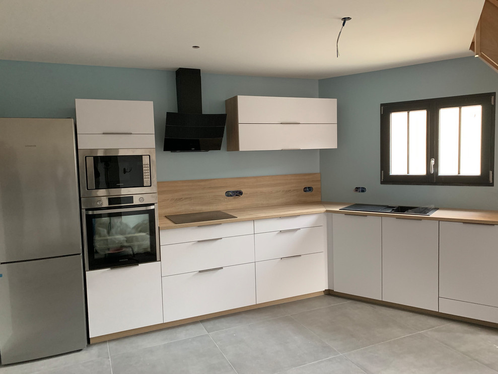 Photo of a small contemporary l-shaped open plan kitchen in Grenoble with an integrated sink, beaded inset cabinets, white cabinets, wood benchtops, beige splashback, timber splashback, stainless steel appliances, ceramic floors, grey floor and beige benchtop.