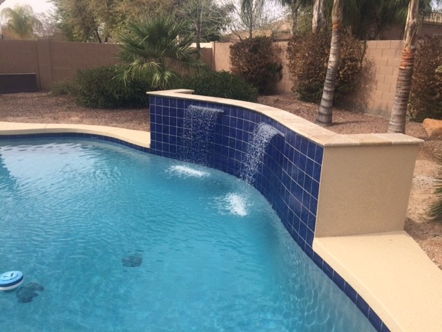 Design ideas for a mid-sized tropical backyard custom-shaped pool in Phoenix with decking.